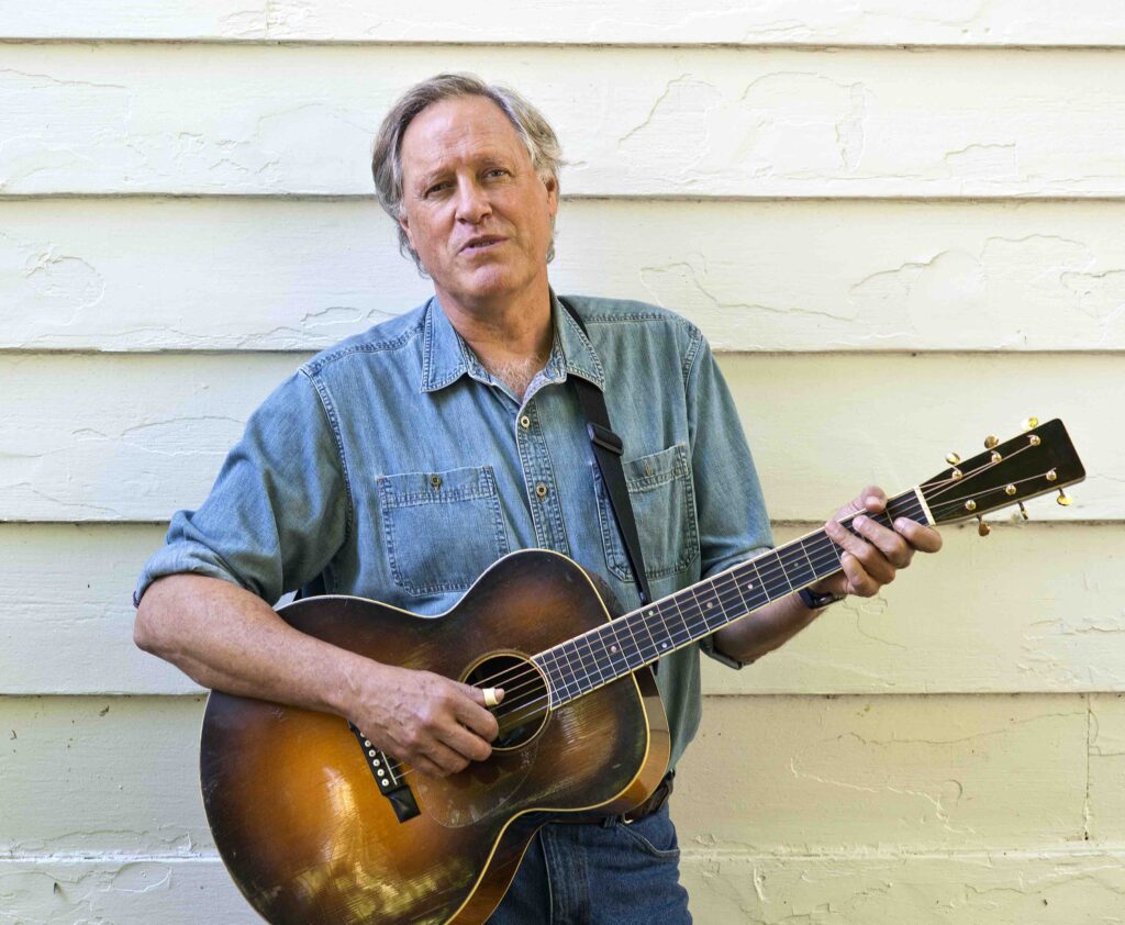 Tom Chapin holding a guitar.