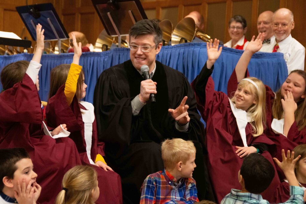Pastor David sitting with children during Mass.